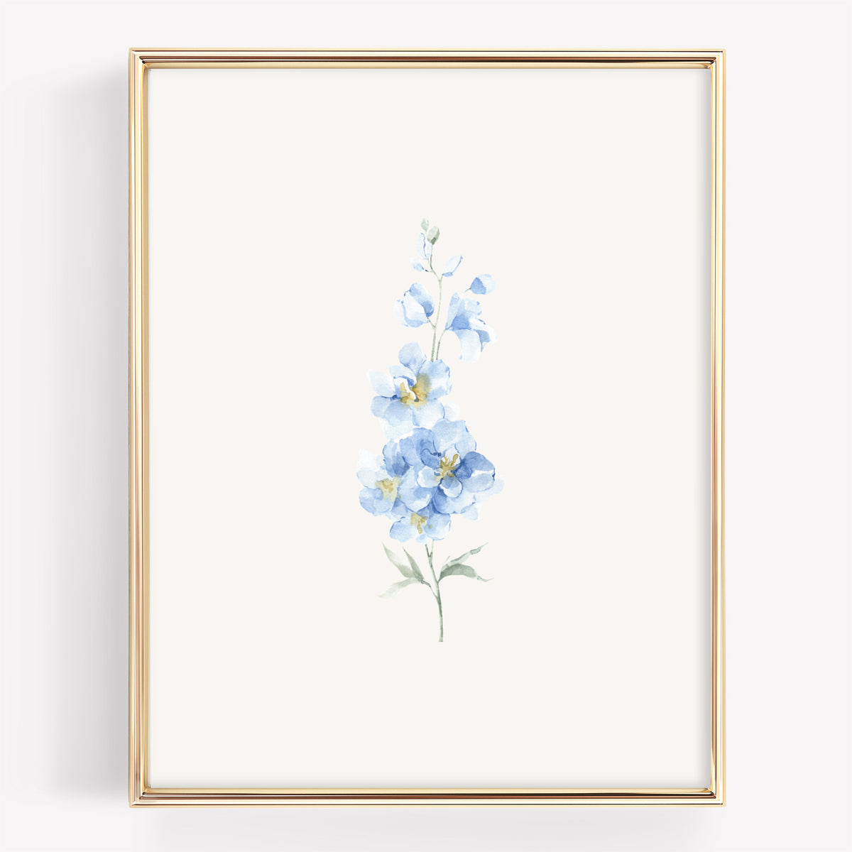 A vertical framed art print featuring a delicate watercolor illustration of light blue flowers with green stems on an off-white background, enclosed in a thin gold frame.