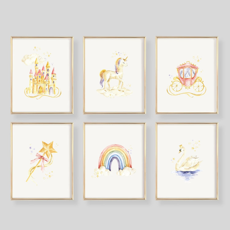 Six framed watercolor art prints arranged in a 2x3 grid on a white wall. The prints feature whimsical illustrations of a castle, unicorn, carriage, wand, rainbow, and swan in soft pastel colors with gold-toned frames.