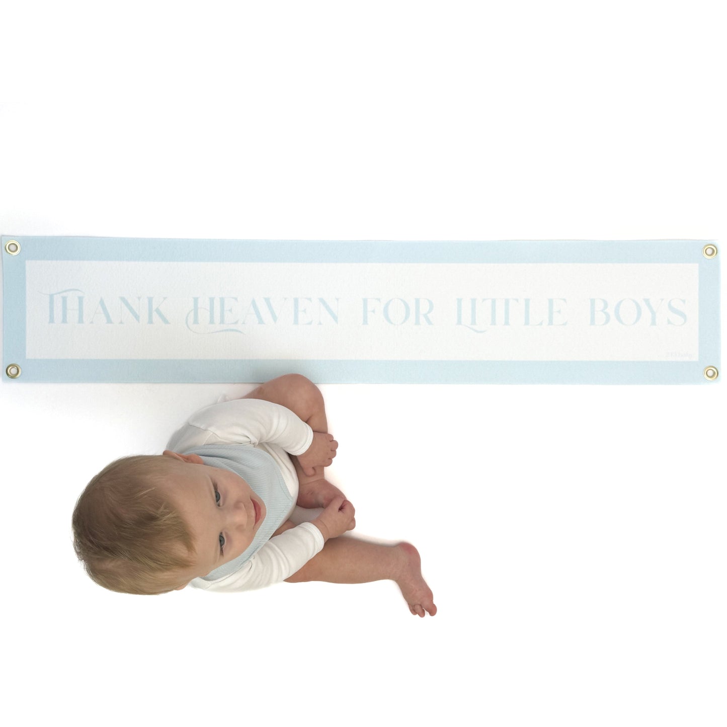 baby sitting on a luxury nursery banner above reading 'Thank Heaven for Little Boys' on a white background