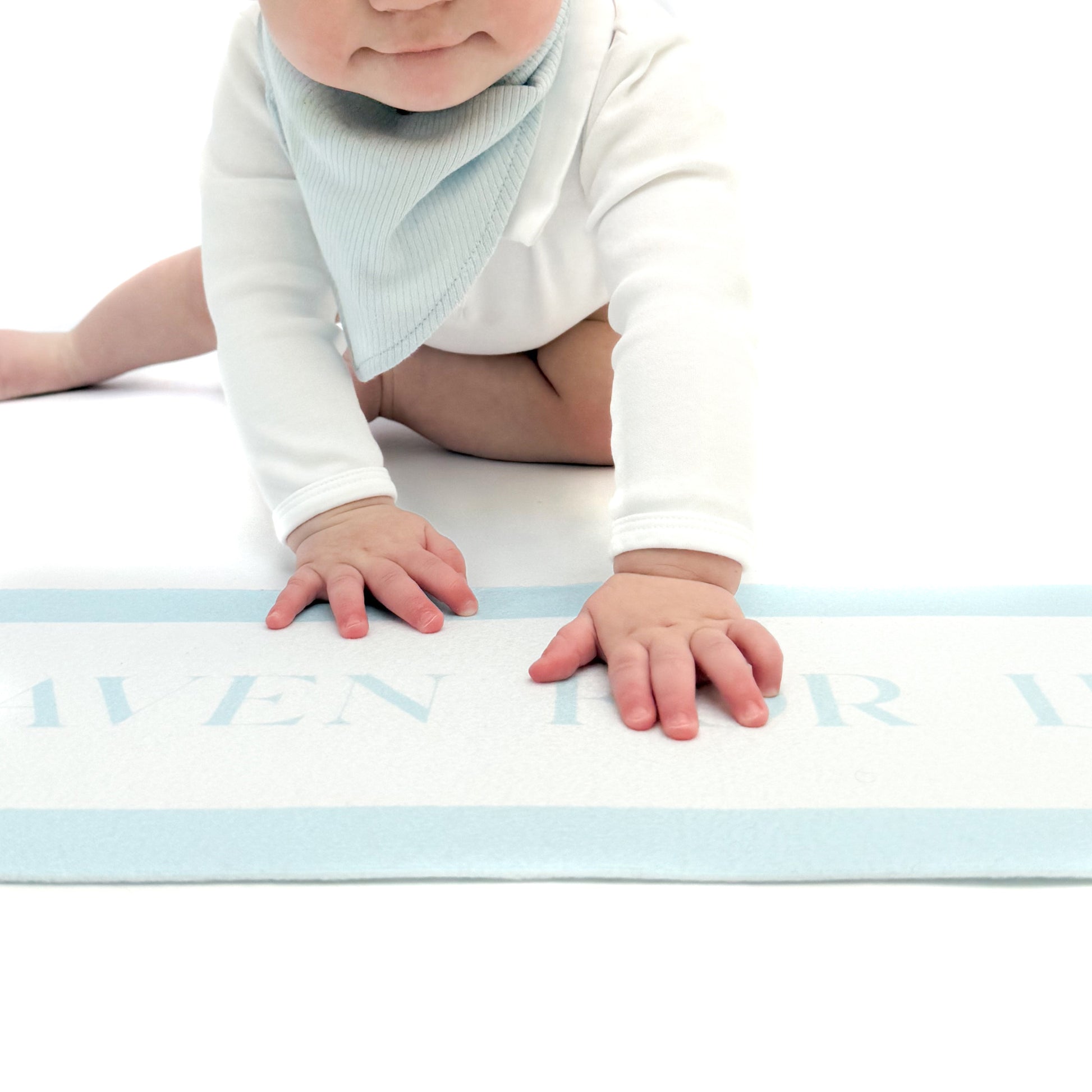 Baby crawling on a white banner with a blue border, wearing a light blue bib.