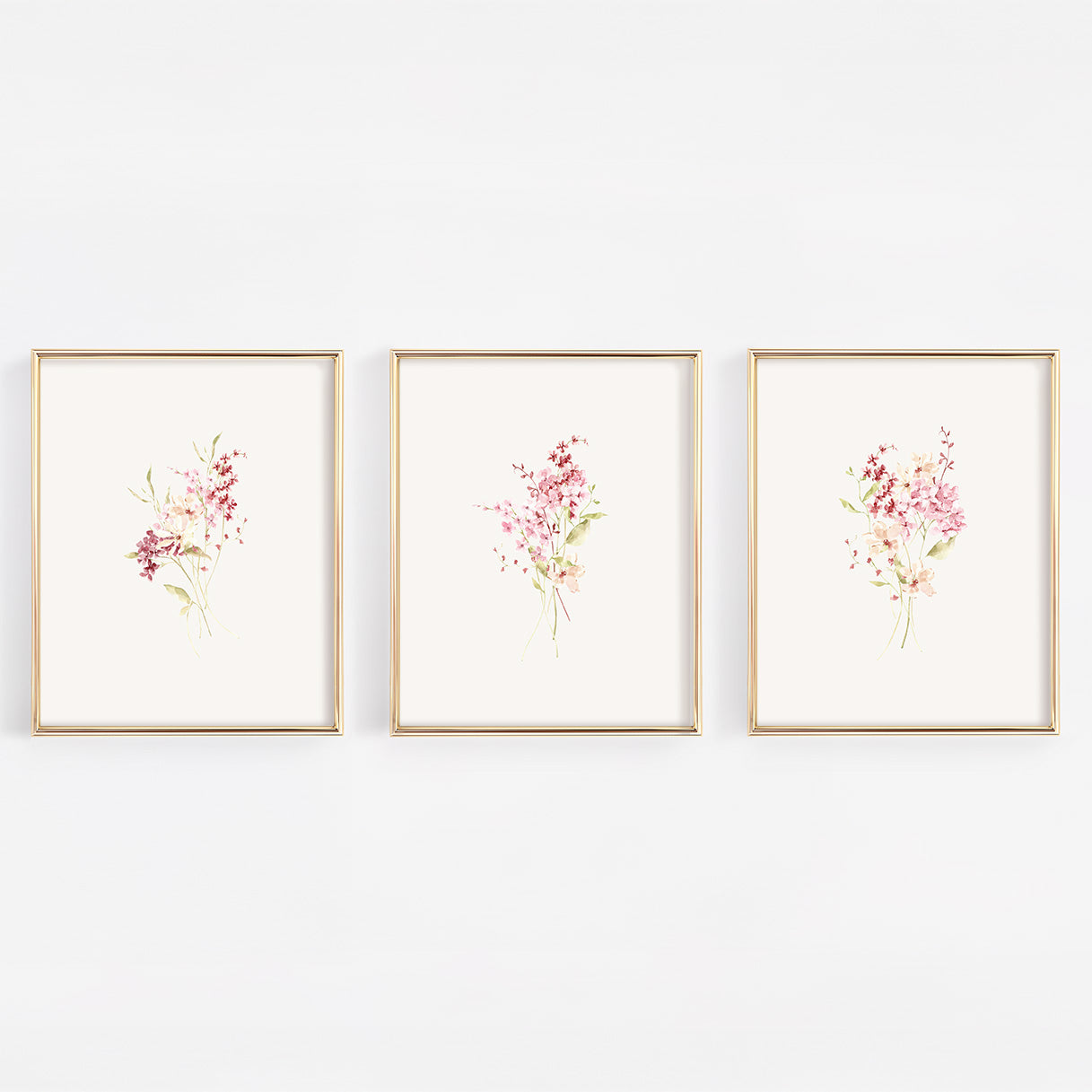 A set of three vertical gold-framed nursery wall art prints featuring different botanical bundles of dusty rose and burgundy wildflowers on a crisp white background.