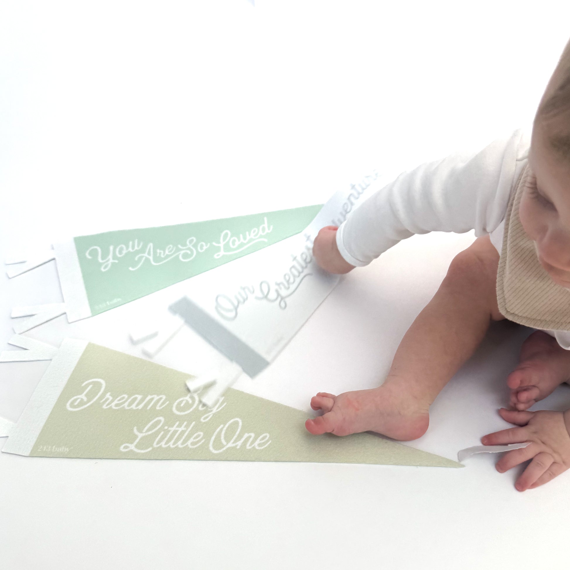 Baby playing with luxury felt decor flags on a white surface