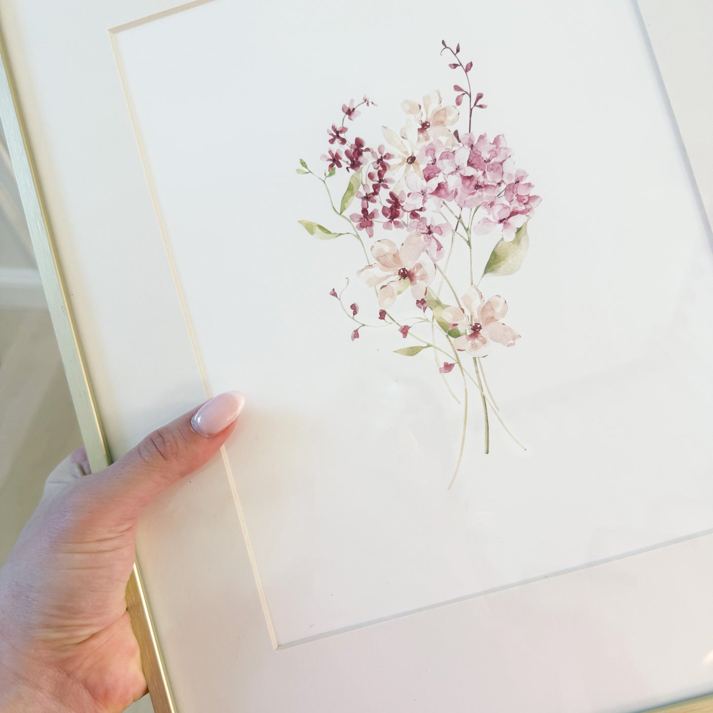 Picture of a burgundy and pink watercolor bouquet against a white background and in a gold frame.