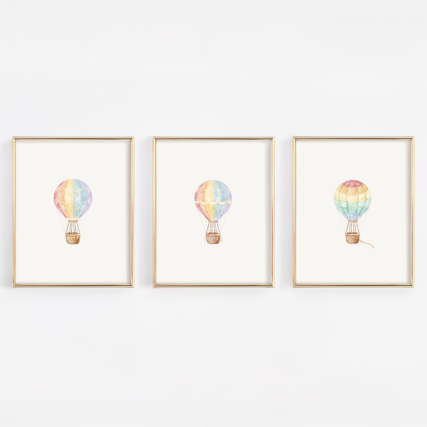 Three framed prints of watercolor colorful hot air balloons on a white wall.