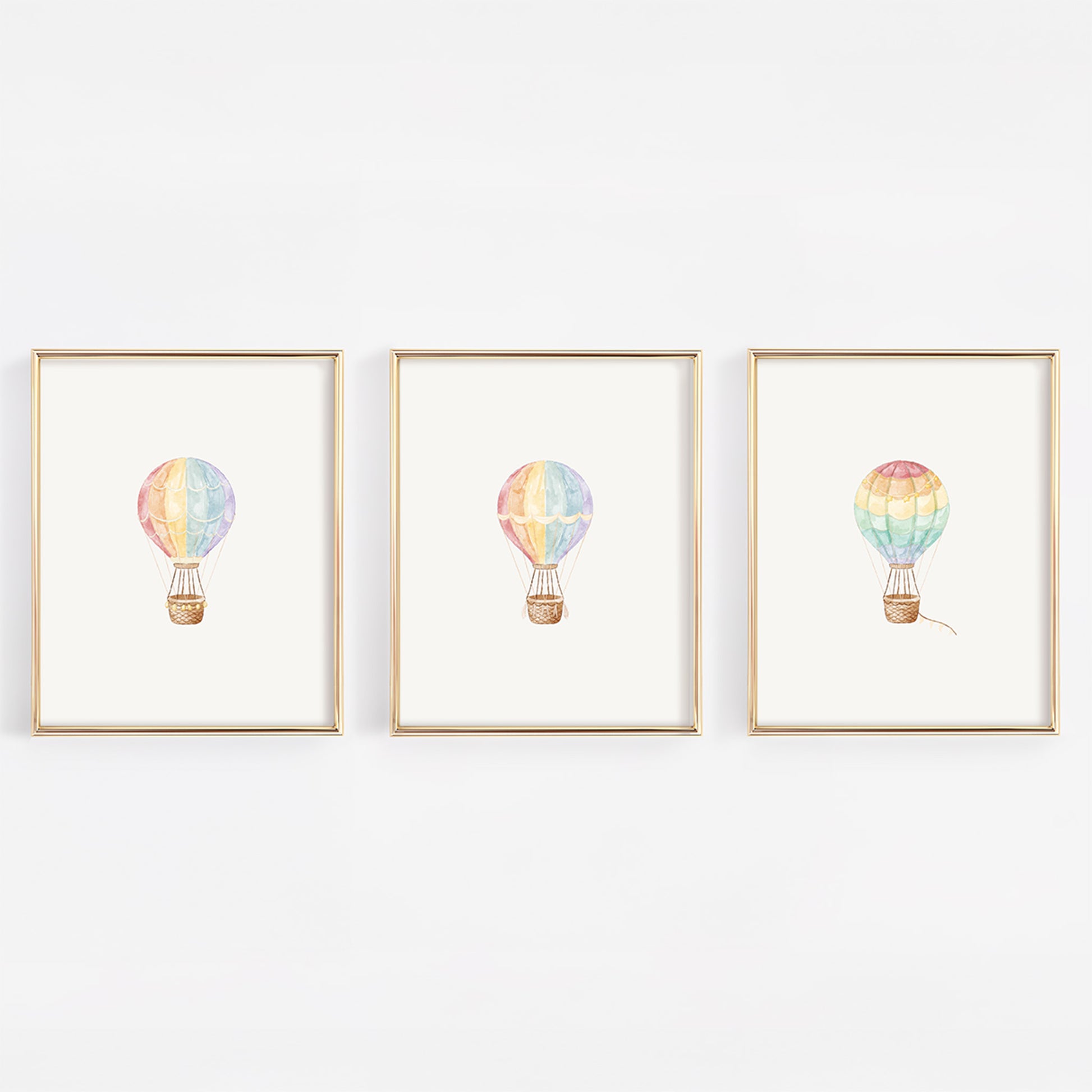 Three framed prints of watercolor colorful hot air balloons on a white wall.