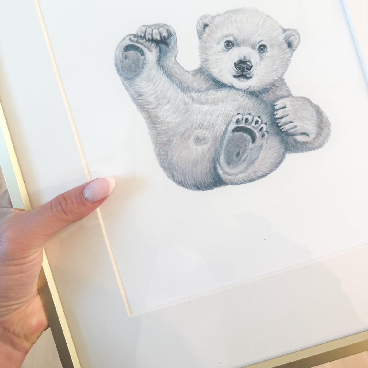 Watercolor polar bear playing against white paper with a gold frame