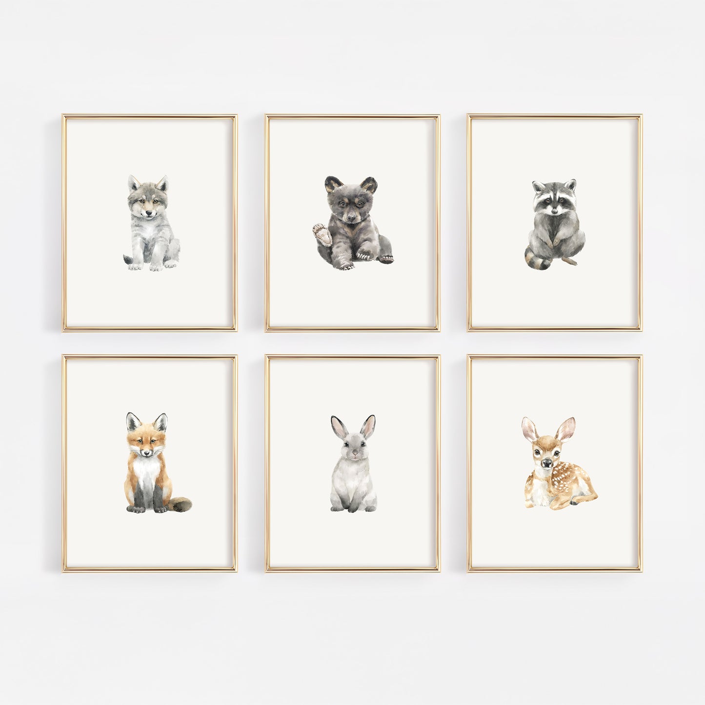 Six woodland creature art prints in gold frames including wolf, bear, raccoon, fox, bunny, and deer
