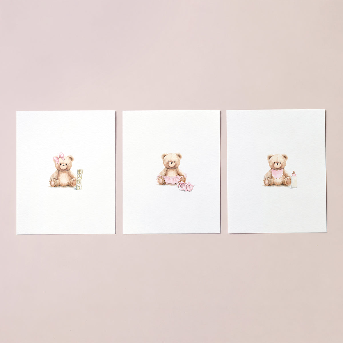 Unframed set of 3 watercolor baby girl teddy bear art prints with wooden blocks, ballet slippers, and bottle on blush pink.