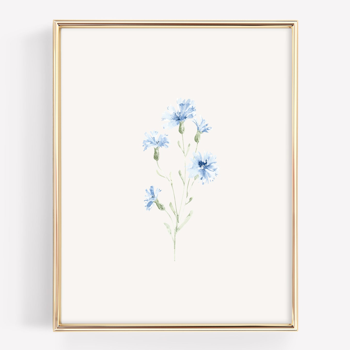 A vertical framed art print featuring a delicate watercolor illustration of blue cornflowers on an off-white background, enclosed in a thin gold frame.