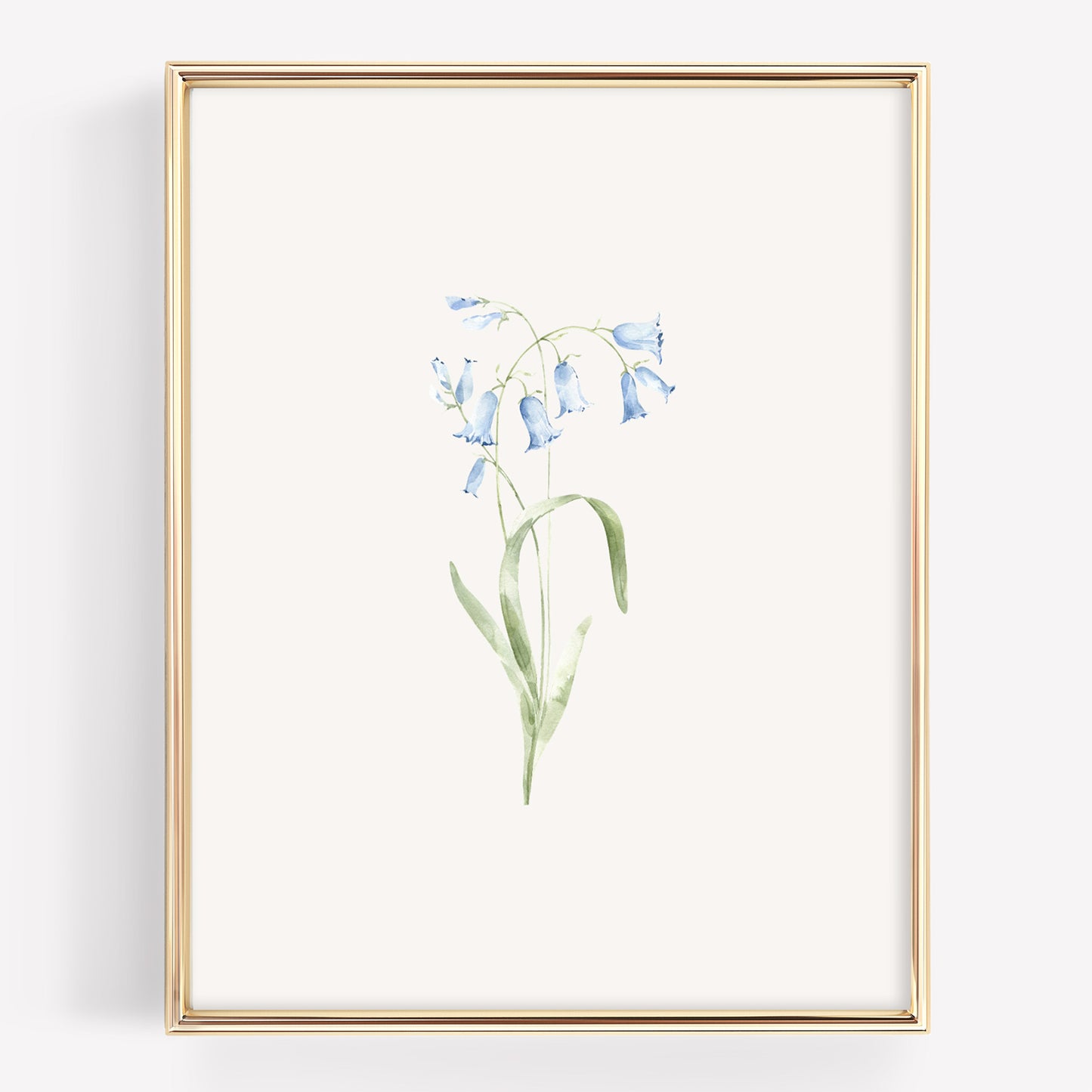 A framed botanical art print featuring a delicate watercolor illustration of light blue bellflowers with green stems on an off-white background, enclosed in a thin gold frame.