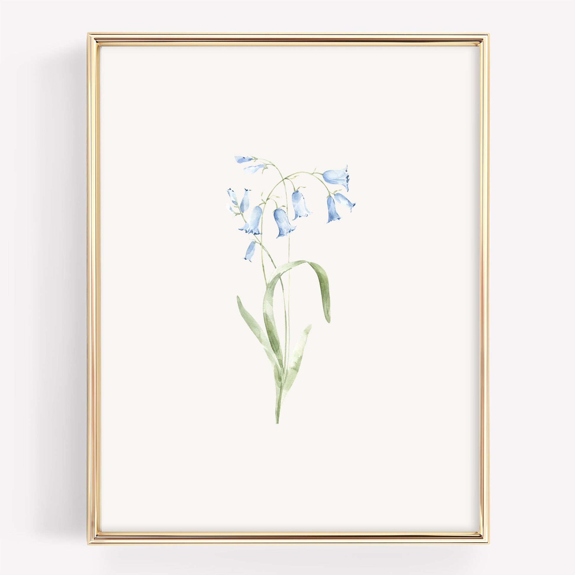 A framed botanical art print featuring a delicate watercolor illustration of light blue bellflowers with green stems on an off-white background, enclosed in a thin gold frame.