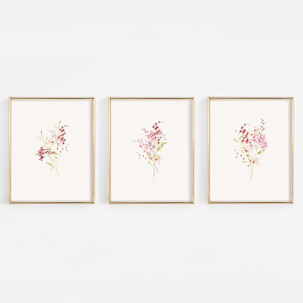 A set of three vertical gold-framed nursery wall art prints featuring different botanical bundles of dusty rose and burgundy wildflowers on a crisp white background.