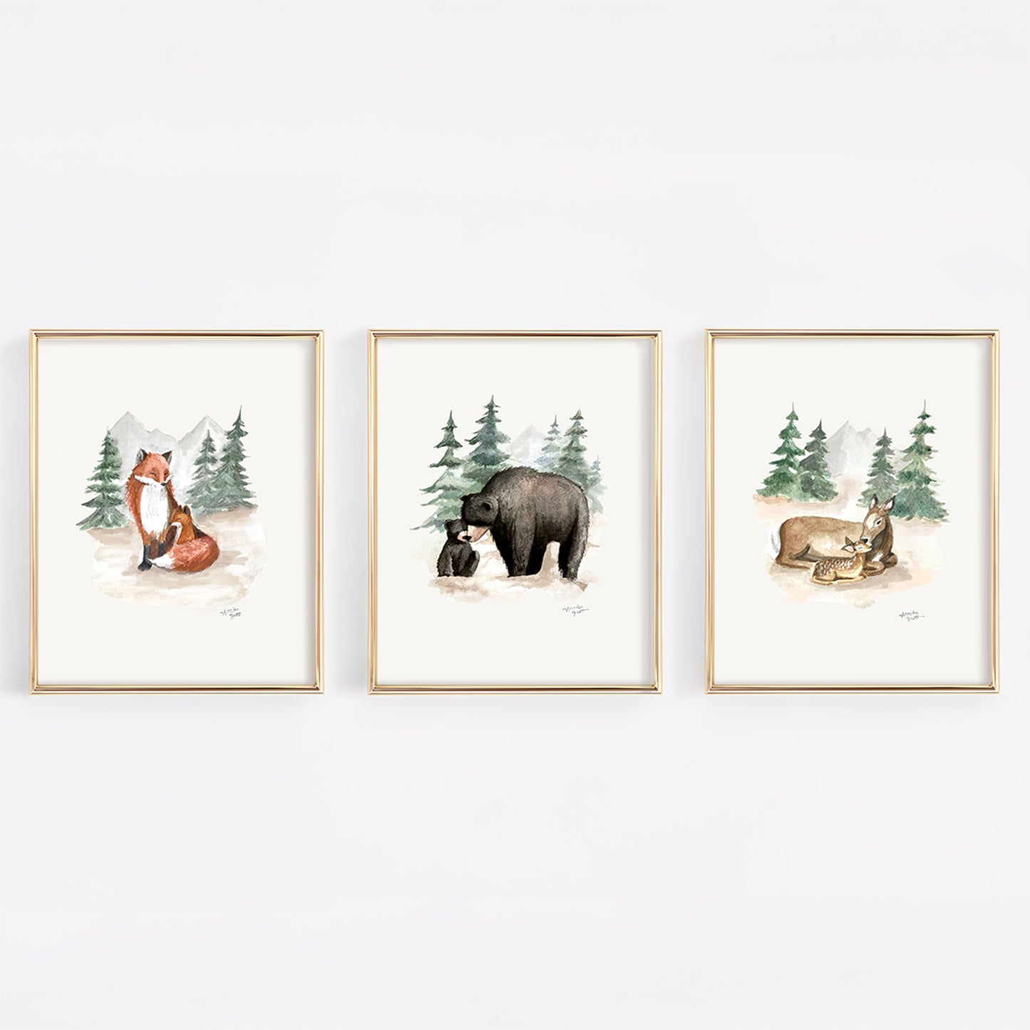 Three framed prints of forest animals on a white wall including black bears, foxes, and deer. 