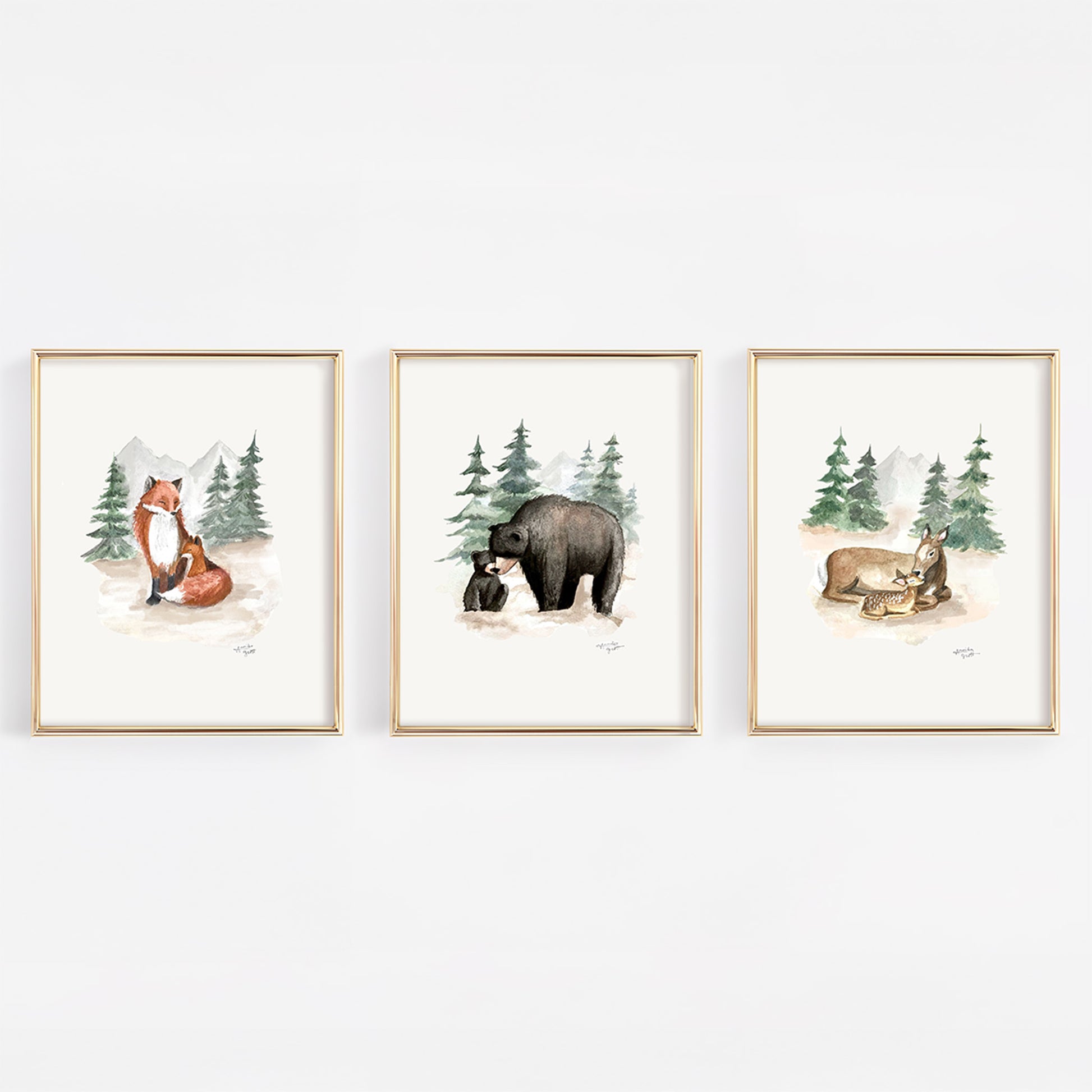 Three framed prints of forest animals on a white wall including black bears, foxes, and deer. 