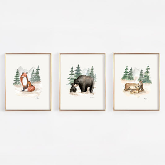 Three framed prints of forest animals on a white wall including black bears, foxes, and deer. 