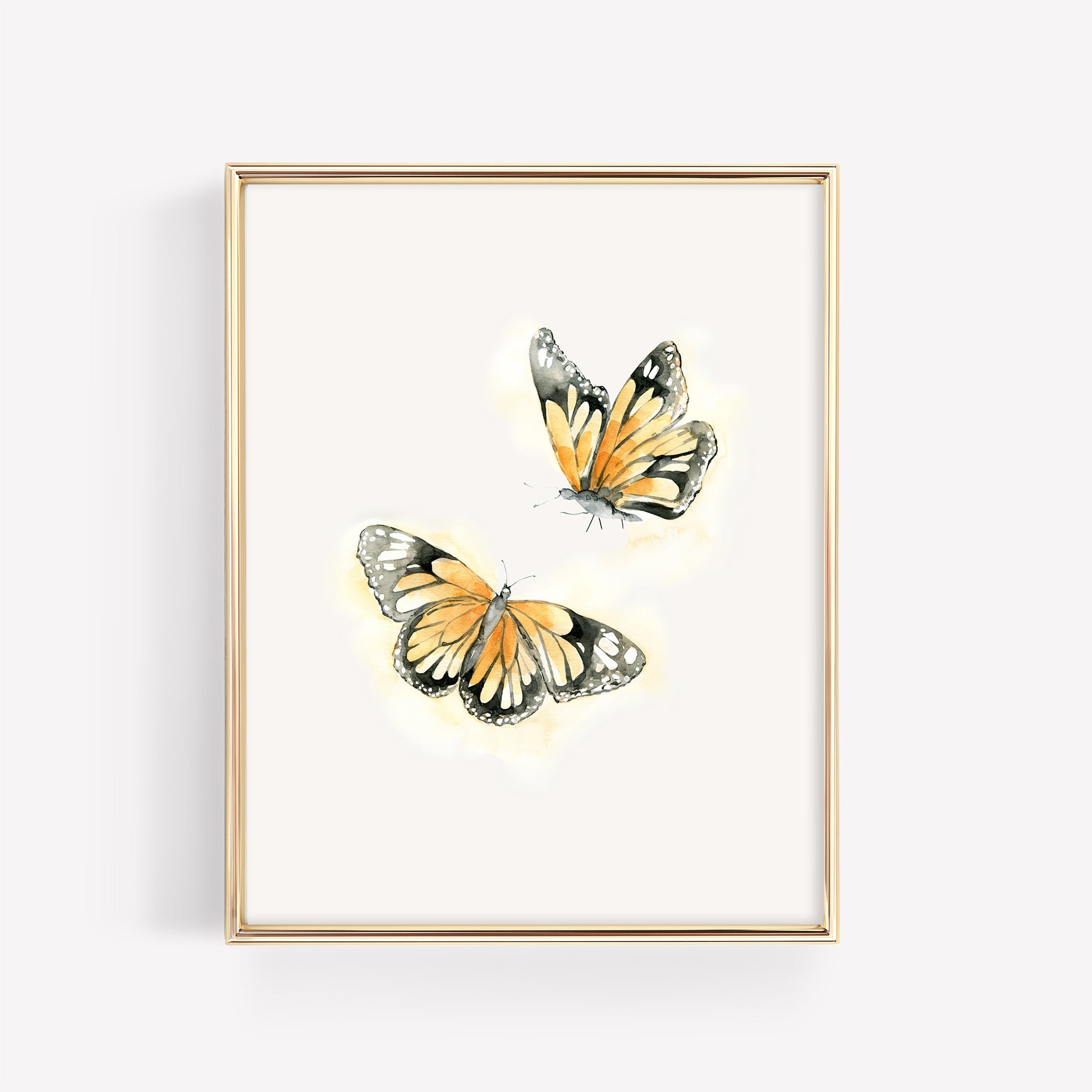 Two vibrant monarch butterflies in a vertical gold frame, featuring a soft watercolor orange glow and delicate black detailing on a clean white background.