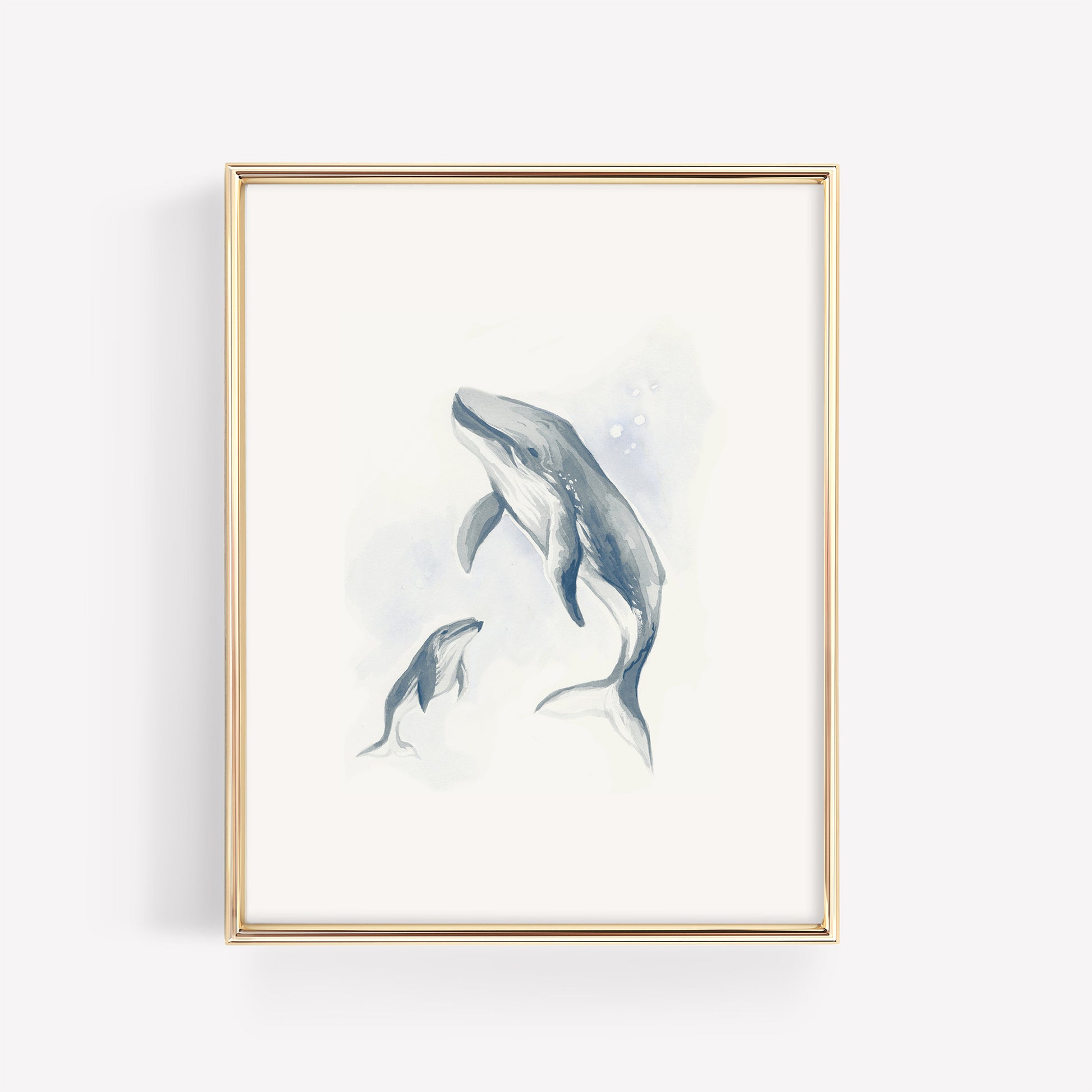 A serene watercolor illustration of a mother humpback whale and her baby calf in deep ocean blue, displayed in a minimalist gold frame for a nautical nursery.