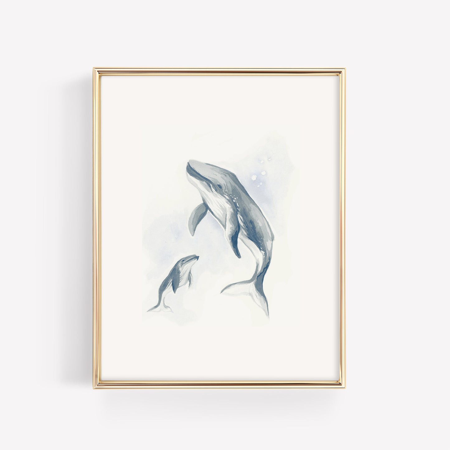 A serene watercolor illustration of a mother humpback whale and her baby calf in deep ocean blue, displayed in a minimalist gold frame for a nautical nursery.