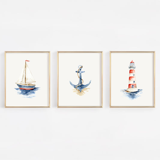Three framed watercolor nautical art prints hanging on a white wall, featuring a sailboat, an anchor, and a red-and-white lighthouse.