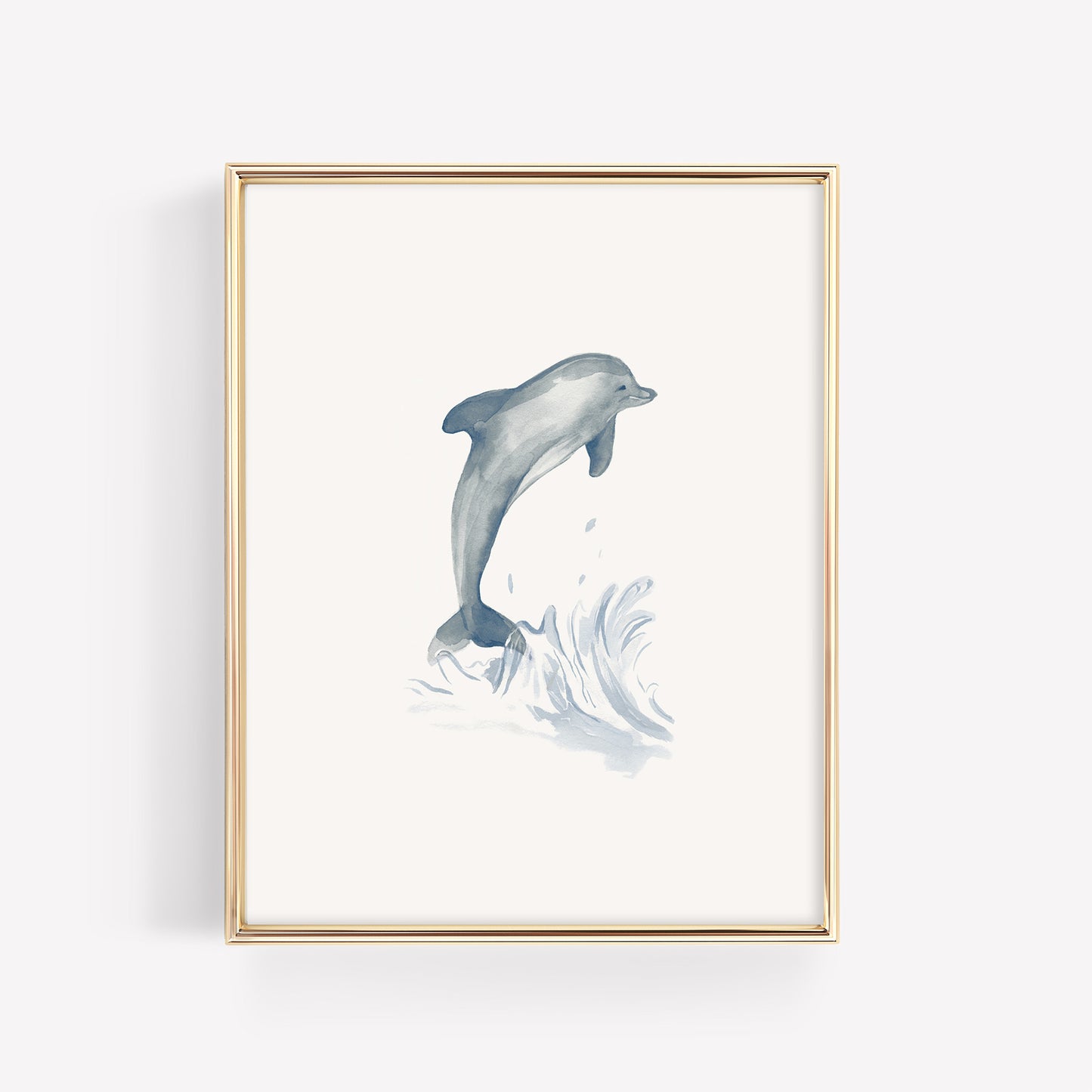 A playful blue watercolor dolphin jumping, featured in a thin gold nursery frame on a crisp white mat for a sea life bedroom theme.