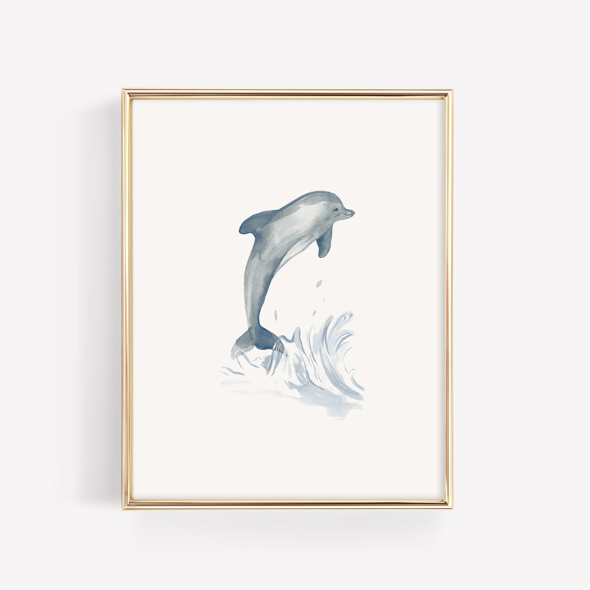 A playful blue watercolor dolphin jumping, featured in a thin gold nursery frame on a crisp white mat for a sea life bedroom theme.