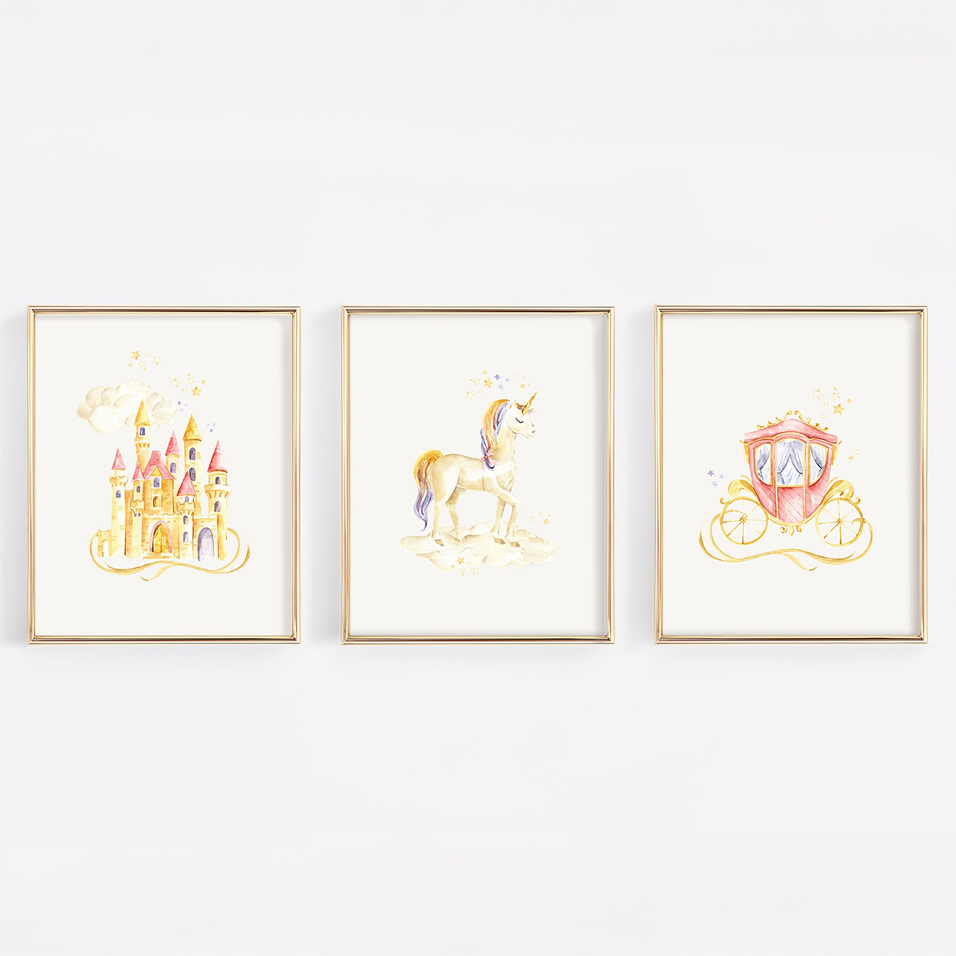Three framed watercolor art prints featuring a golden castle, a unicorn, and a pink carriage, displayed side-by-side on a white wall.