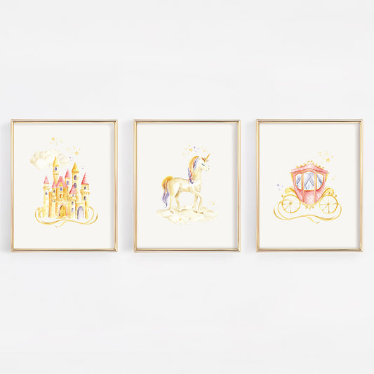 Three framed watercolor art prints featuring a golden castle, a unicorn, and a pink carriage, displayed side-by-side on a white wall.