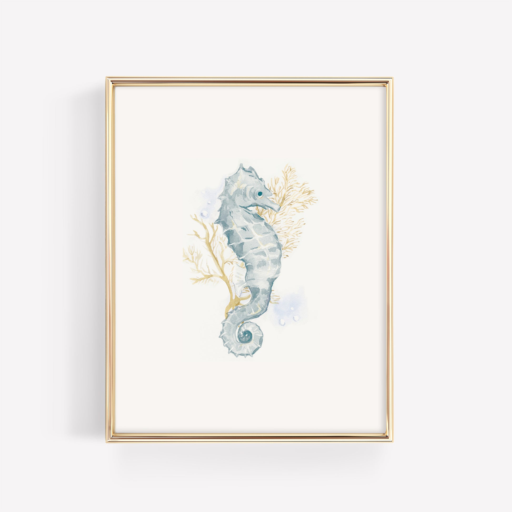 A dainty watercolor seahorse in soft blue and teal tones swimming near a branch of vibrant gold coral, featured in a sleek metallic gold frame for a coastal baby room.