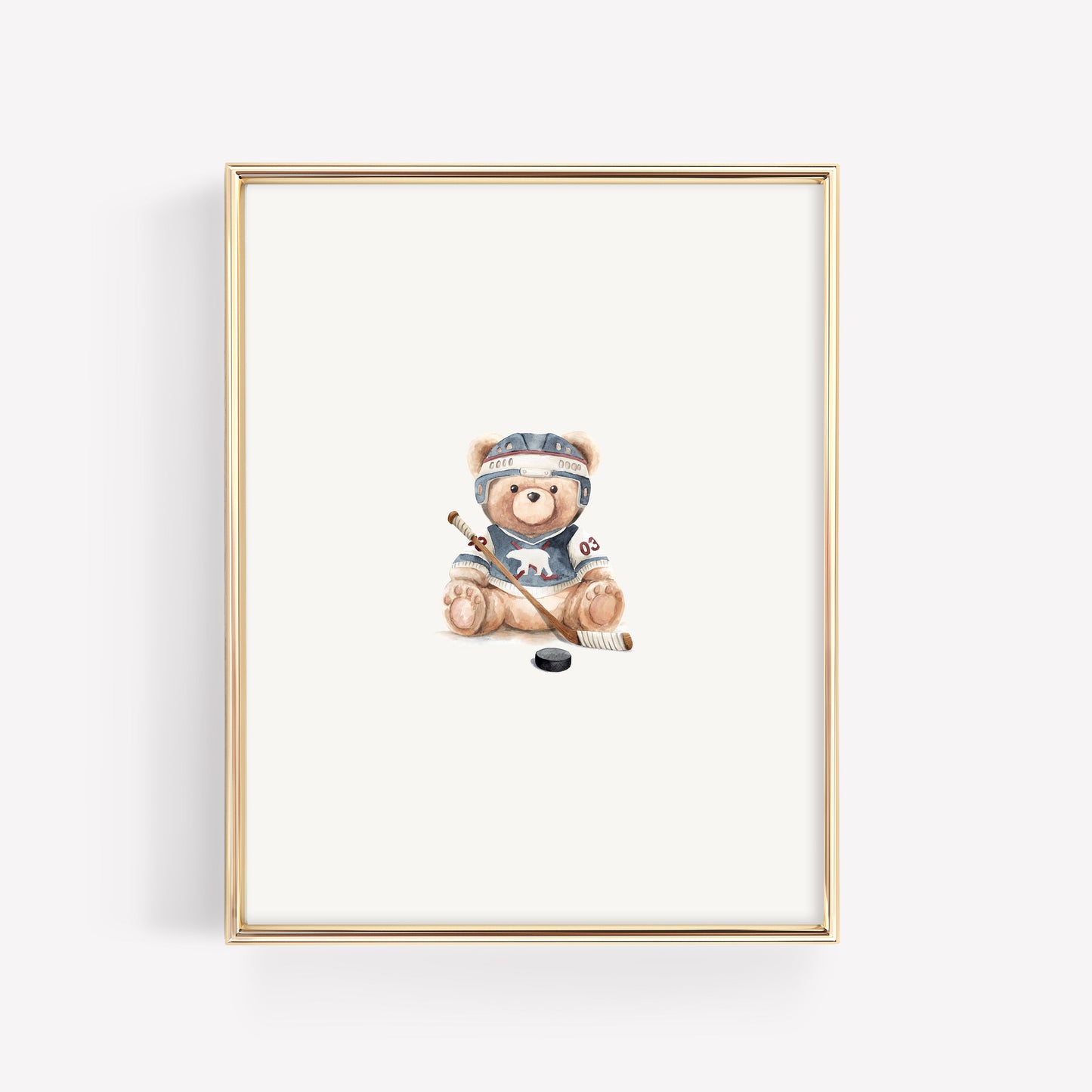 A framed art print featuring a watercolor illustration of a teddy bear wearing a hockey helmet and jersey, sitting with a hockey stick and puck, set in a thin gold frame against a white background.