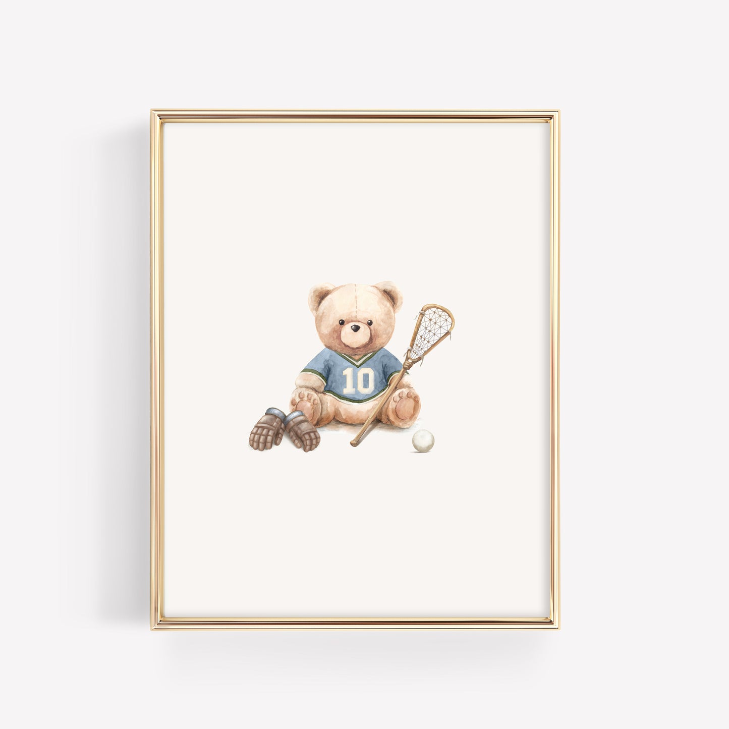 A framed art print featuring a teddy bear wearing a blue lacrosse jersey with the number 10, holding a lacrosse stick next to a white lacrosse ball. The print is housed in a thin gold frame and is displayed against a clean white background.