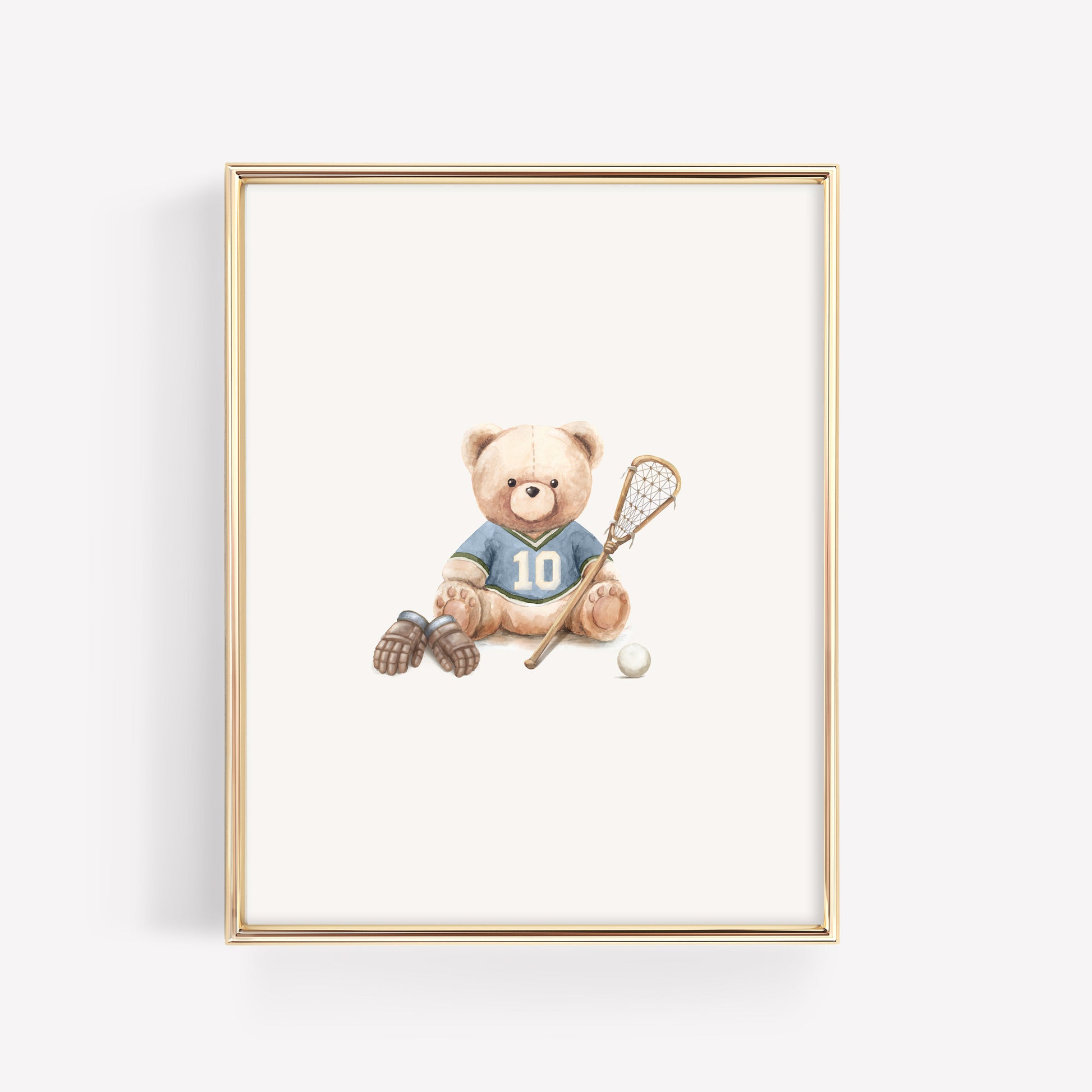 A framed art print featuring a teddy bear wearing a blue lacrosse jersey with the number 10, holding a lacrosse stick next to a white lacrosse ball. The print is housed in a thin gold frame and is displayed against a clean white background.
