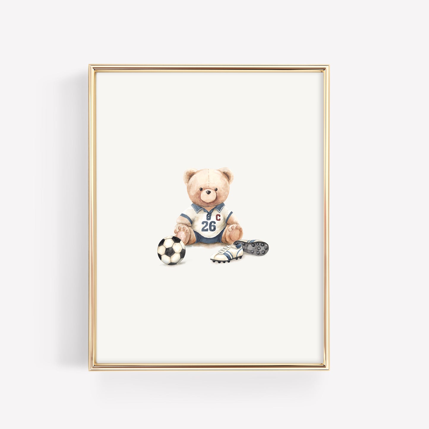 A framed art print featuring a teddy bear wearing a blue soccer jersey with the number 26, sitting next to a soccer ball, a cleat, and a small ball, displayed in a thin gold frame against a light gray background.