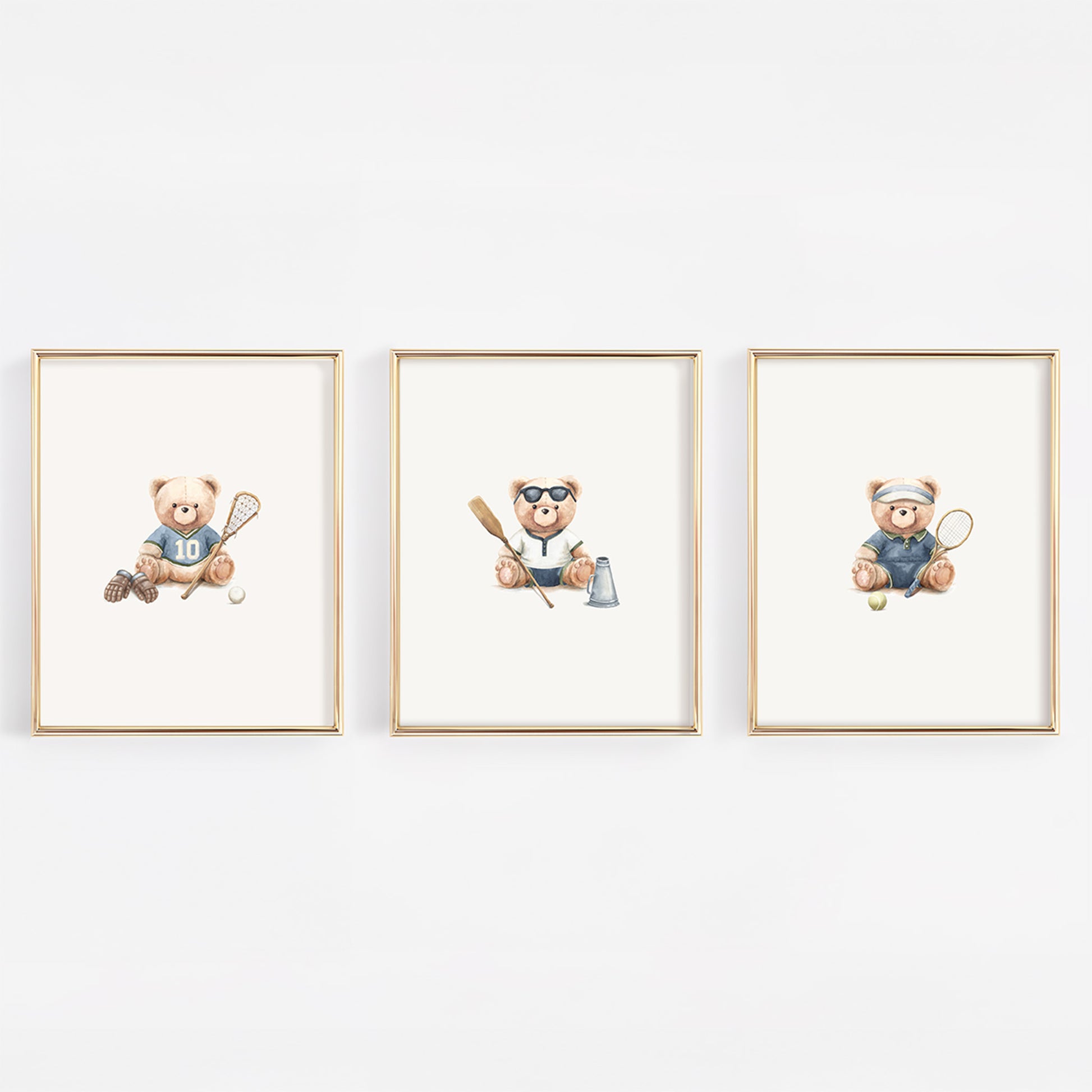 Three framed watercolor prints of teddy bears playing sports, displayed side-by-side on a white wall. The left bear plays lacrosse, the middle bear rows crew and the right bear plays tennis.