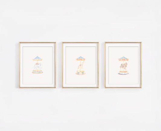 Set of three watercolor carousel animal nursery prints featuring a tiger, giraffe, and elephant on merry-go-round poles. Whimsical carnival themed baby room decor in soft gold, blush, and blue tones.