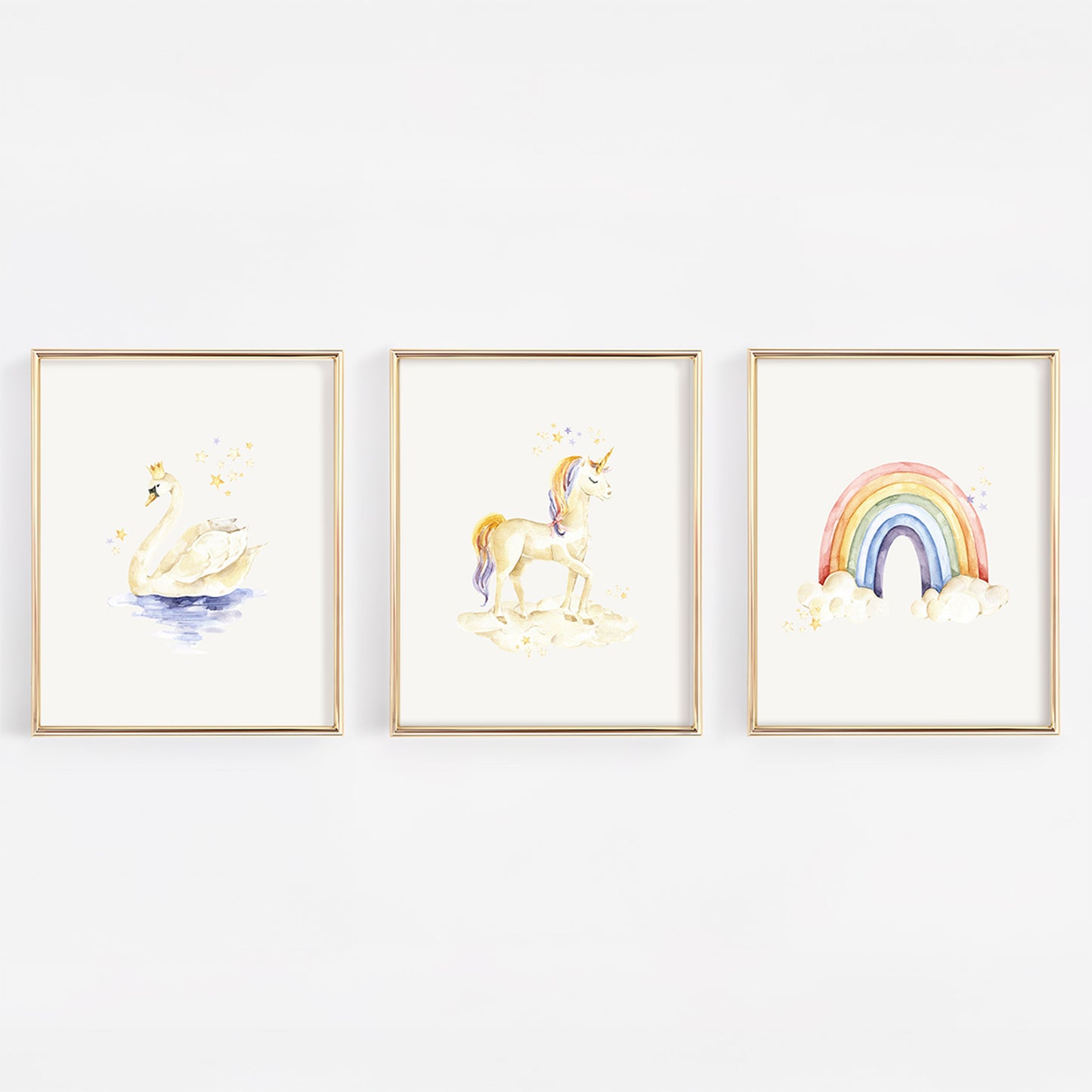 Three framed watercolor art prints hanging on a white wall, featuring a swan, a unicorn, and a rainbow with clouds.