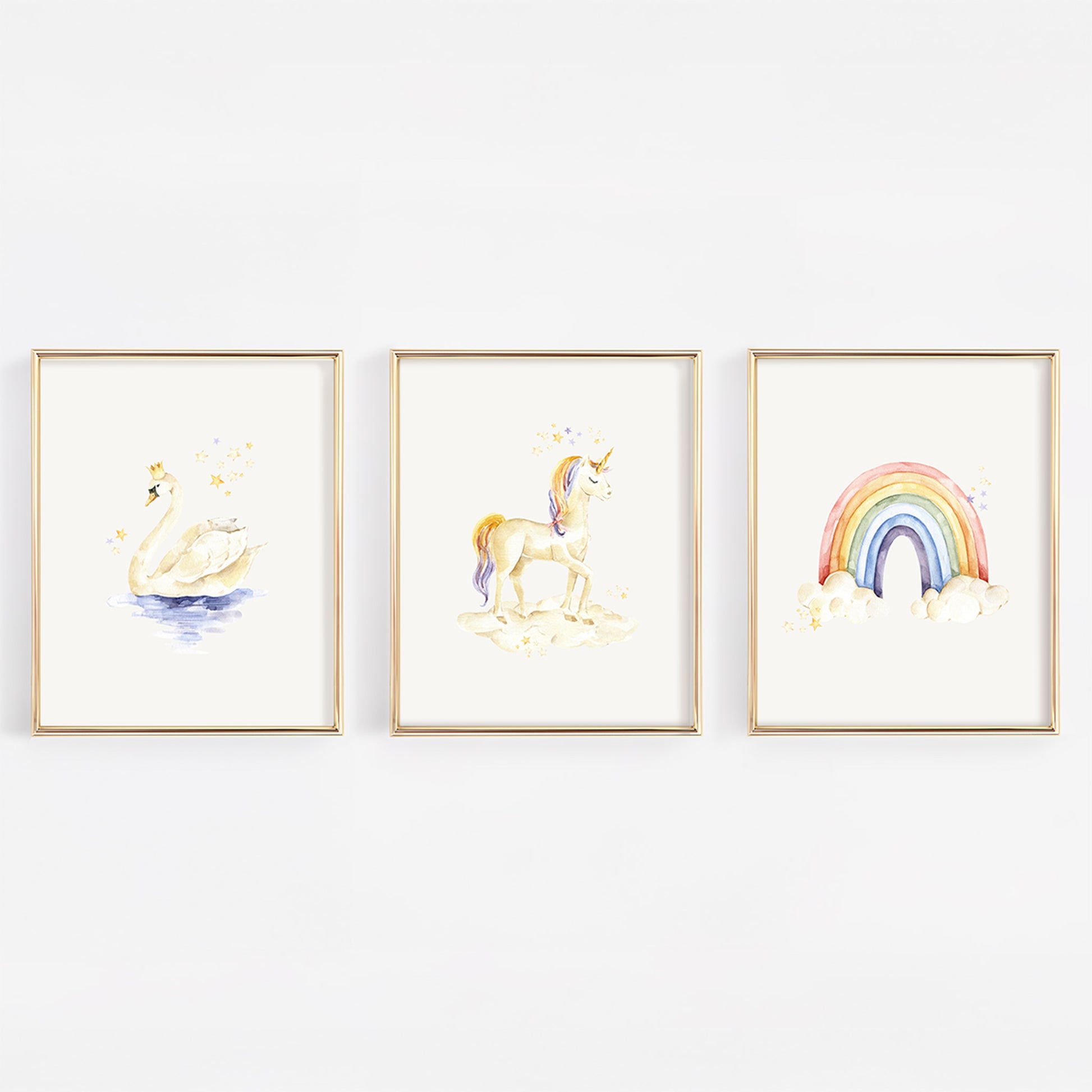 Three framed watercolor art prints hanging on a white wall, featuring a swan, a unicorn, and a rainbow with clouds.
