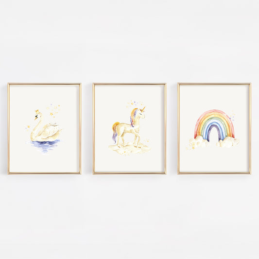 Three framed watercolor art prints hanging on a white wall, featuring a swan, a unicorn, and a rainbow with clouds.