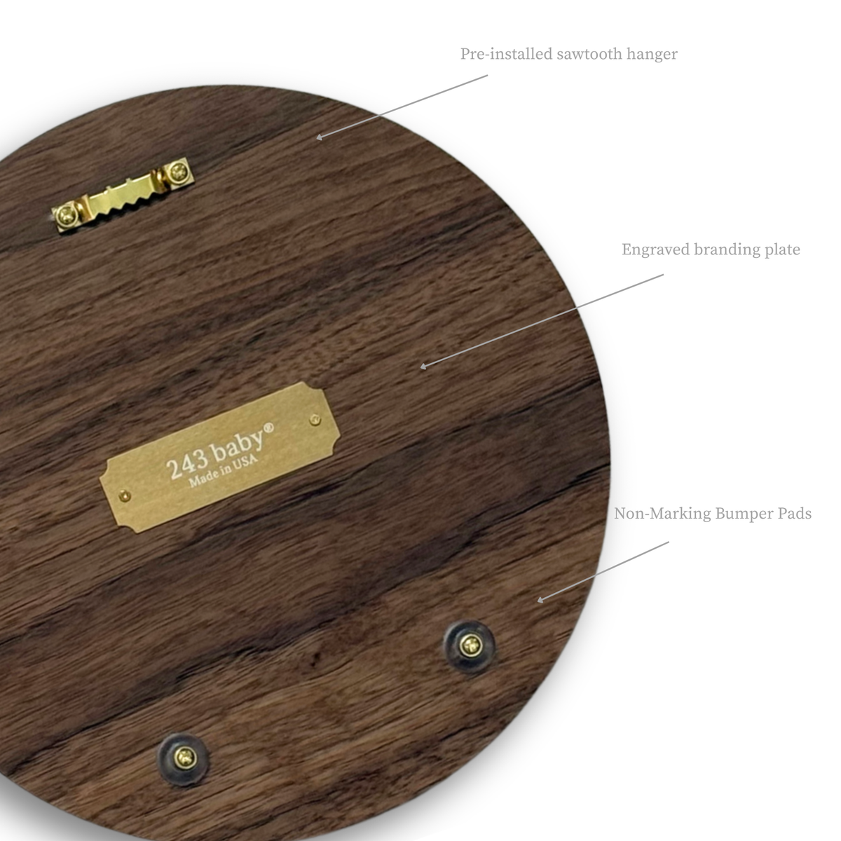 Close-up of the back of a wooden soccer ball nursery wall sign, highlighting the pre-installed sawtooth hanger, clear non-marking rubber bumpers, and a riveted brass '243 baby® Made in USA' nameplate on the natural wood reverse.